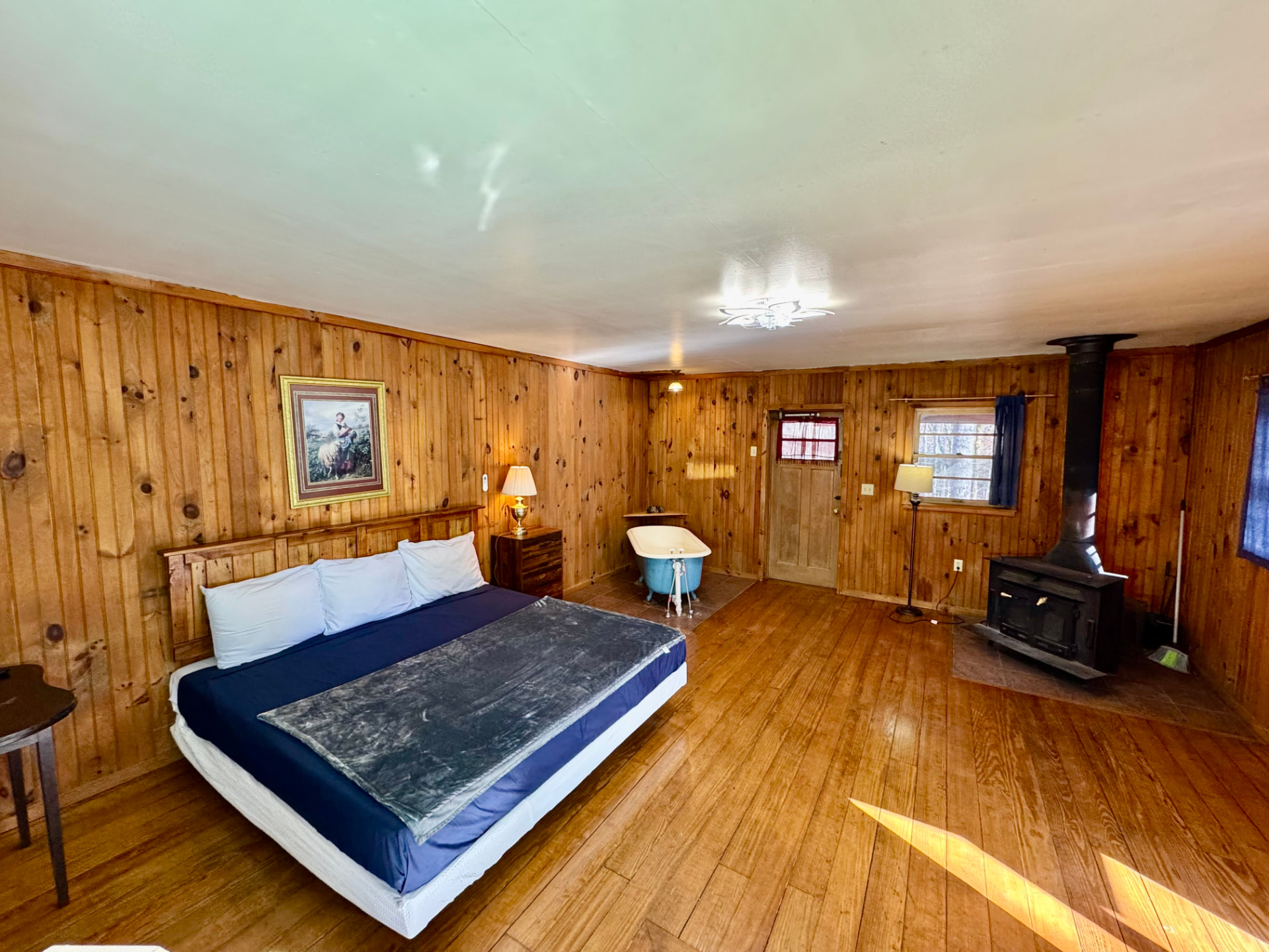 Cabin interior with king bed, wood stove and clawfoot tub