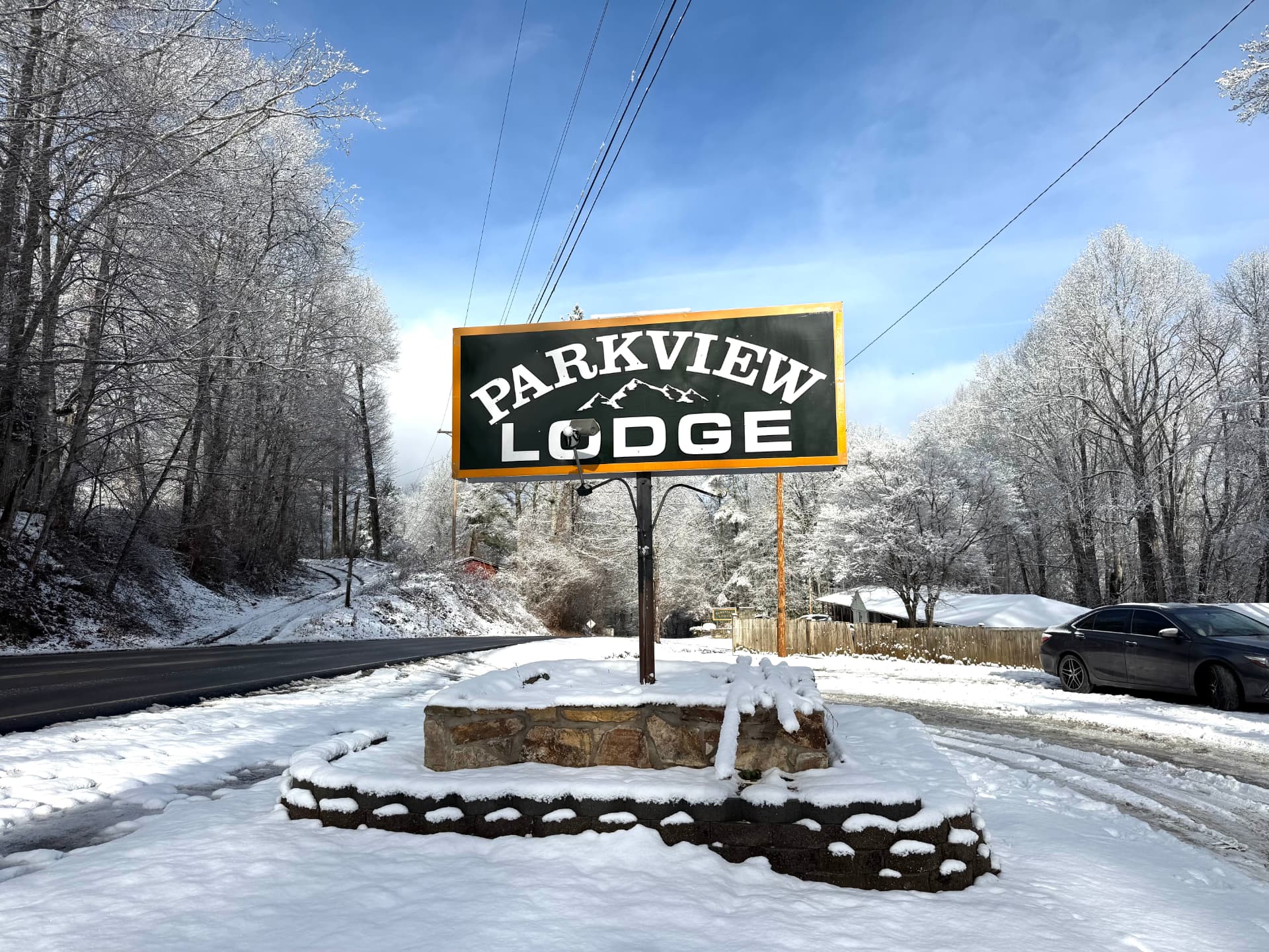 Parkview Lodge sign on a snow-covered stone base beside the road in winter